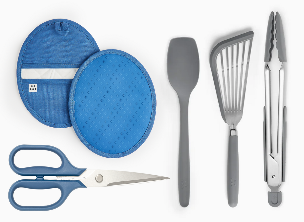 The Prep Starter Kit contains a pair of blue Pot Holders, a pair of blue Kitchen Shears, a gray Spoontula, a Gray Silicone Fish Spatula and a pair of large, gray Silicone Tongs