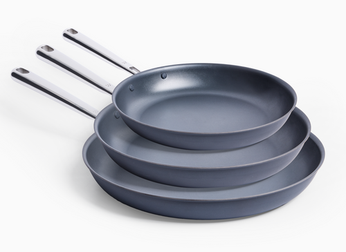 Three Carbon Nonstick™ Frying Pans are stacked on a white background, with the largest 12 inch pan at the bottom, a 10 inch pan in the middle and the smallest 8 inch pan on top. All pans have silver handles and are angled to the right.