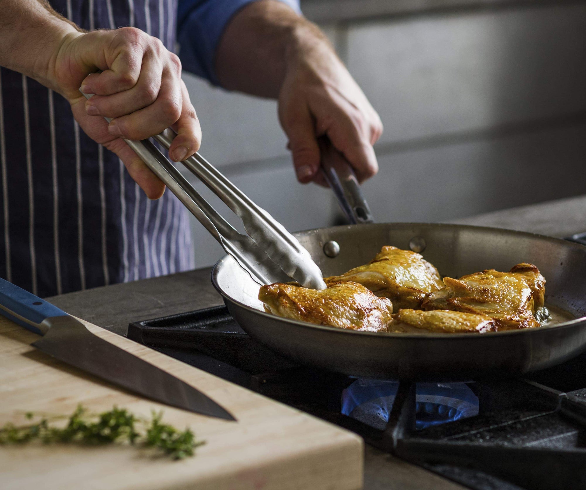 Best cookware: a chef prepares chicken thighs in a stainless steel skillet