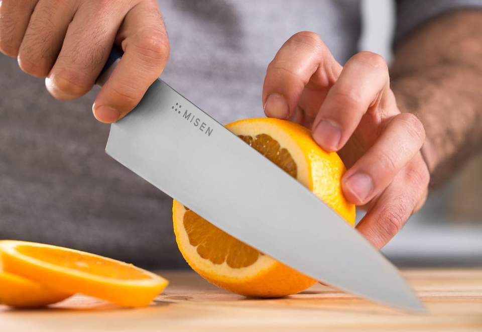 Best steel for knives: A Misen chef's knife slices an orange