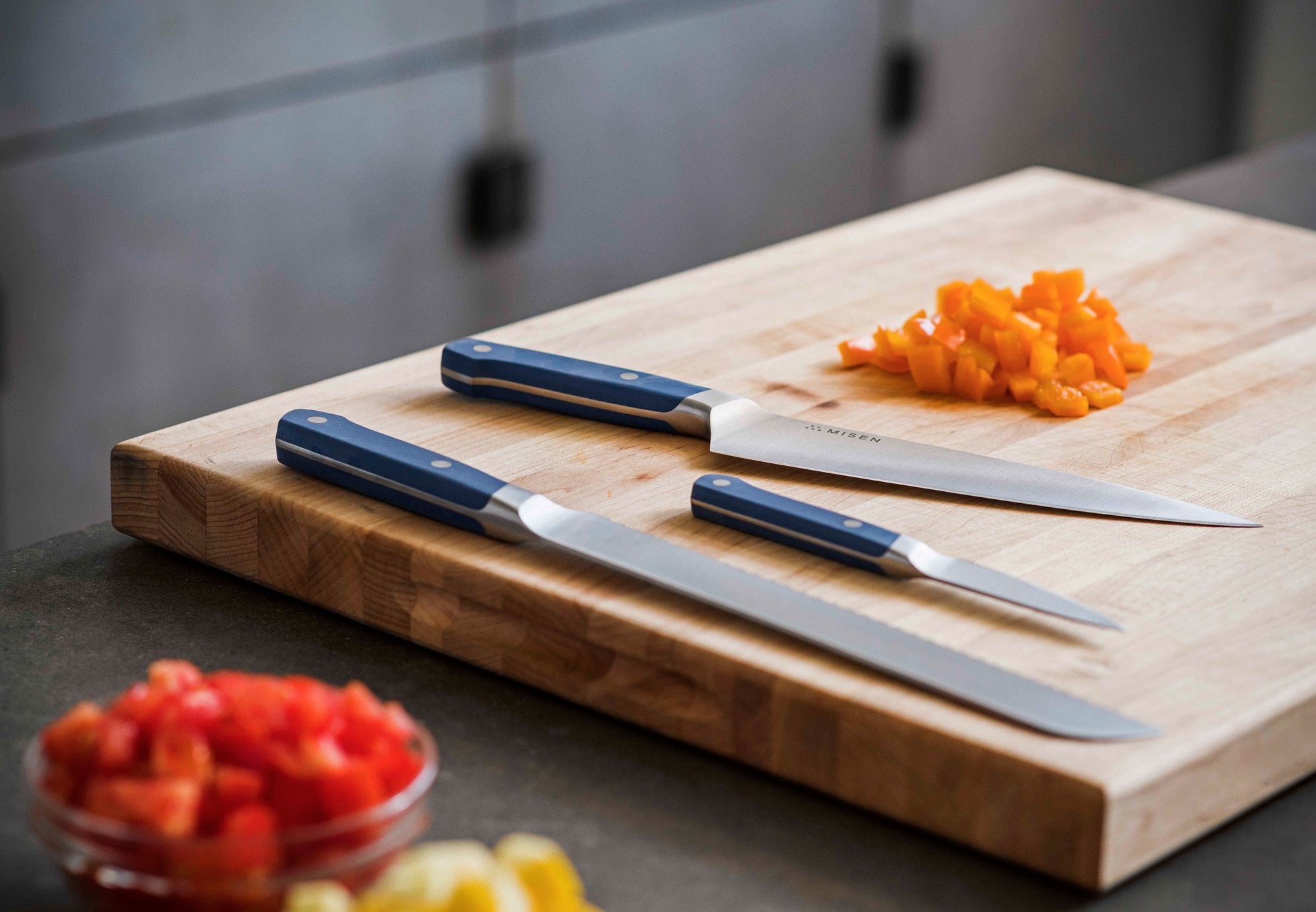 Knife cuts: three knives on a cutting board with finely diced vegetables