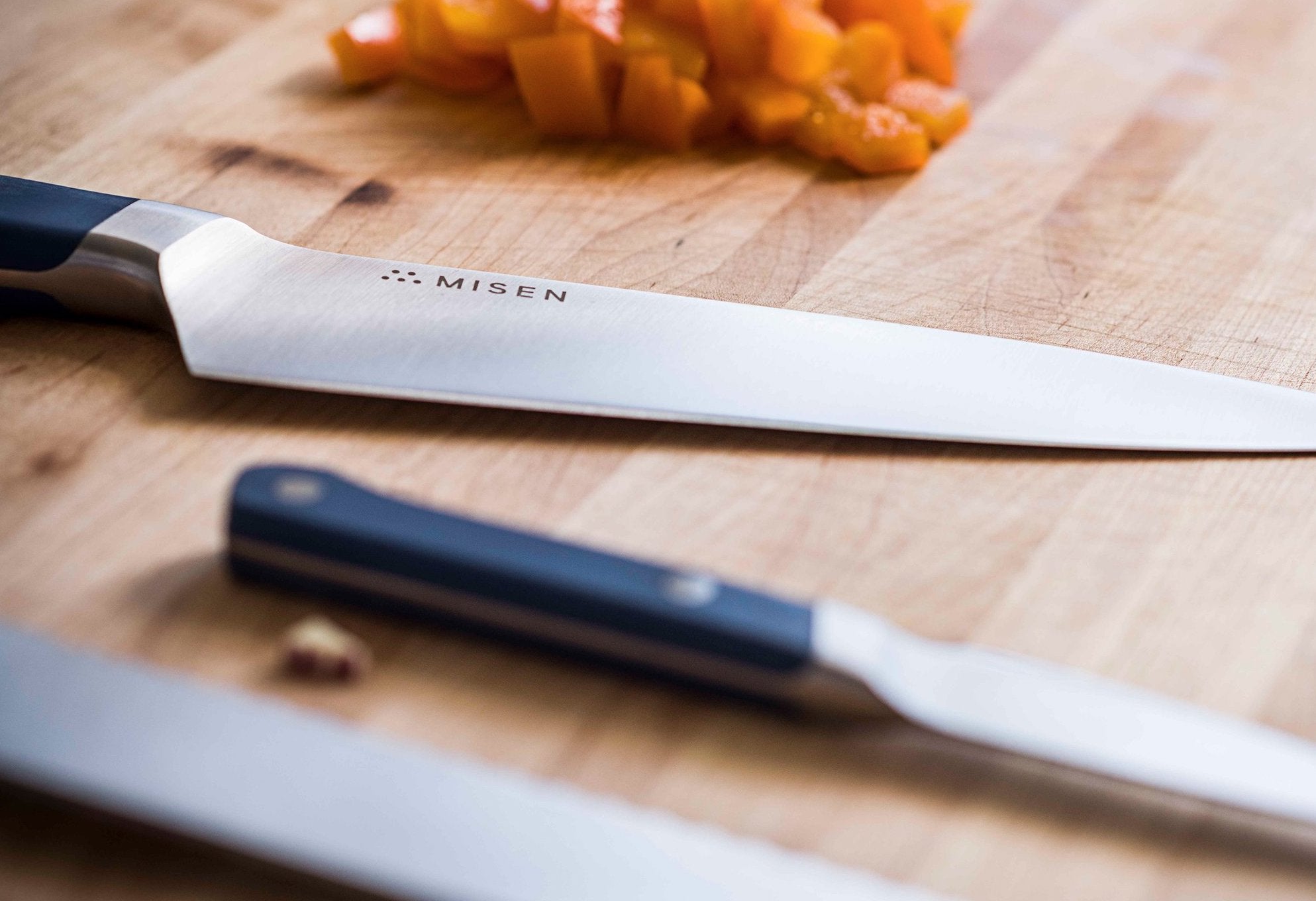 Santoku vs. chef's knife: three knives on a cutting board with diced carrots