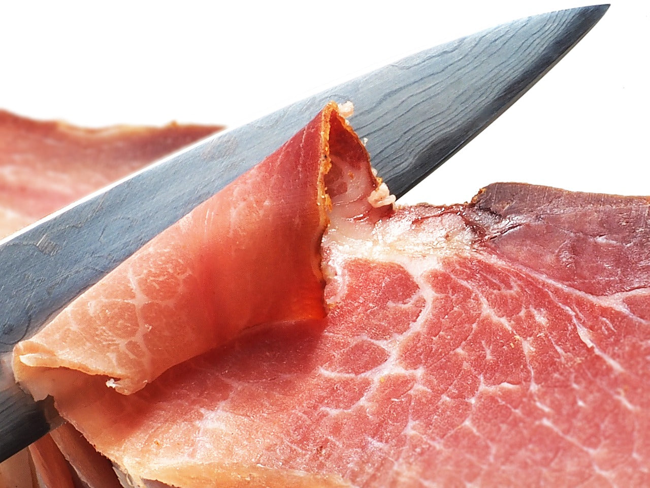 Knife sharpening stone: A knife finely slices prosciutto