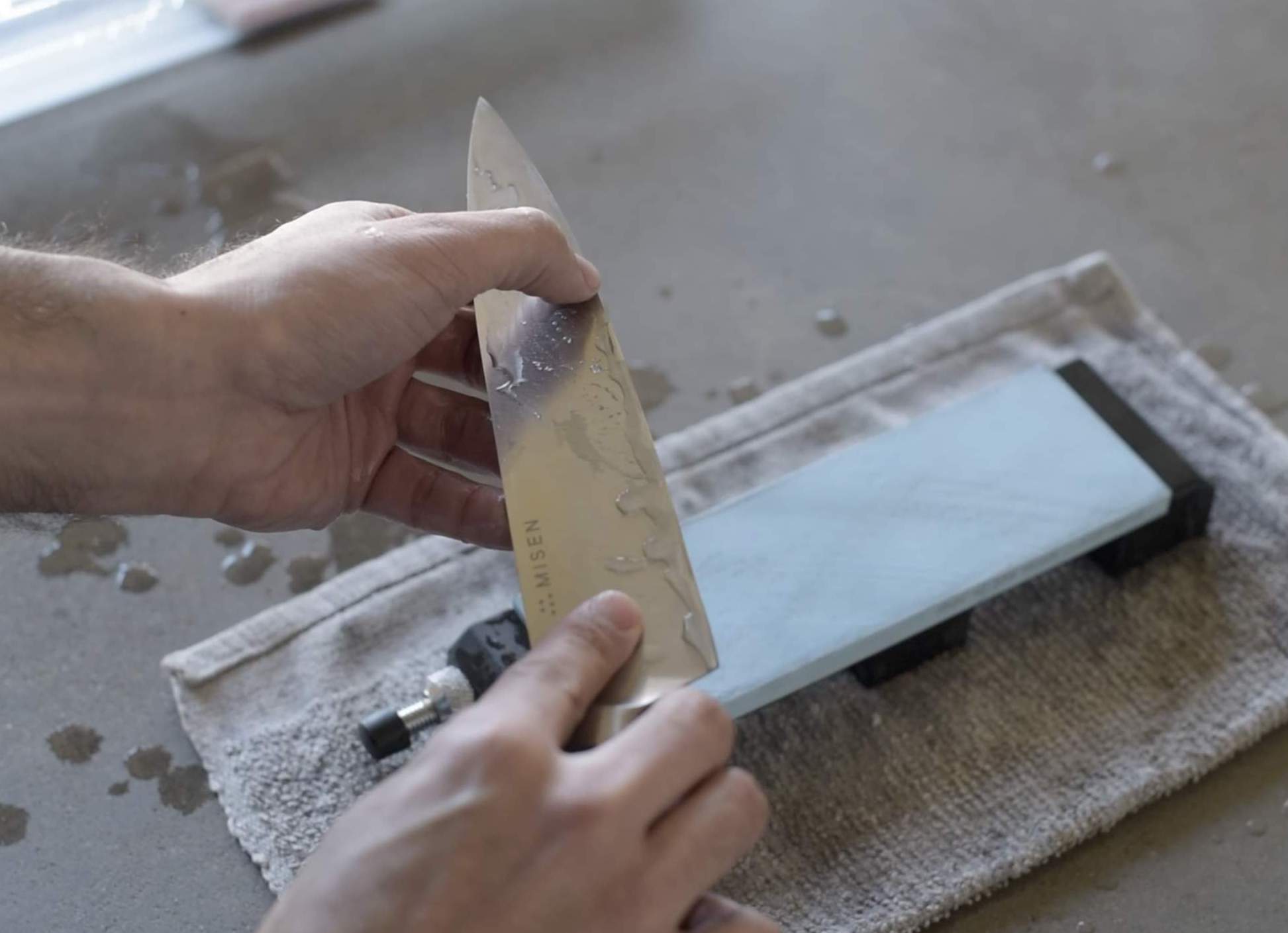 Honing vs. sharpening: A man sharpens a knife using a sharpening stone