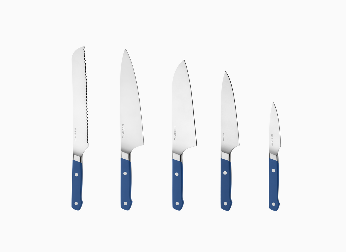 The image displays a set of five Misen knives with blue handles and AUS-10 blades, arranged vertically against a white background. From left to right, the knives decrease in size. The leftmost knife has an 8" serrated blade. The second knife from the left is an 8" chef's knife. The middle knife is an 8" santoku knife. The fourth knife from the left is a 5.5" utility knife. The rightmost knife is a 3.5" paring knife. Each knife has the word "MISEN" faintly visible near the handle on the blade.
