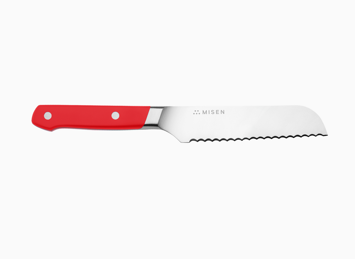 A side view of a red Misen Short Serrated Knife on a white background.