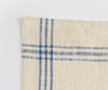 A close-up shot of the corner of a Misen Kitchen Towel, with the stitching and blue stripe pattern clearly visible.