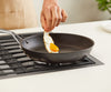 A chef’s hand pulls a fried egg easily off of a Misen Nonstick Pan on a stovetop.