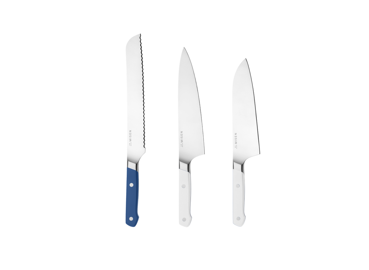 Three Misen knives on white background: serrated bread knife with blue handle and two chef's knives with white handles.
