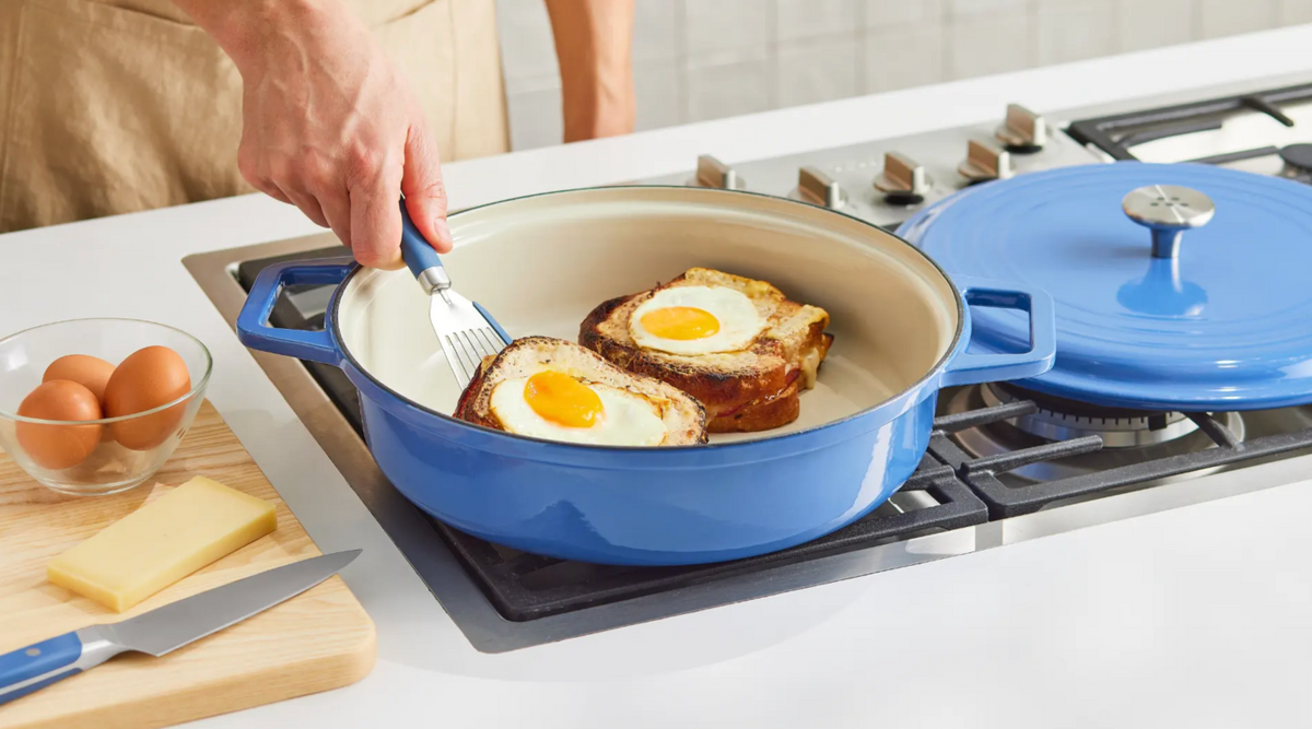 Eggs-in-a-hole toast cooking in a blue enameled cast iron braiser on gas stovetop