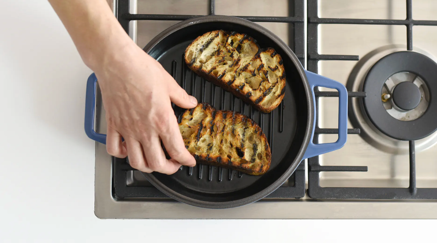 Grilling bread slices on cast iron grill pan over gas stovetop