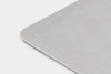 A side-angle view of part of the Misen Bench Scraper’s metal blade, showing its rounded corners, on a white background.