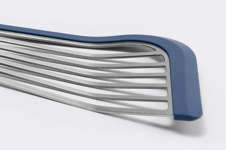 Close view of Blue Misen Silicone Fish Spatula’s slotted metal head, showing blue silicone edge lining and a slight bend.