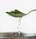 Fresh snap peas lifted from boiling water on a slotted spoon while blanching