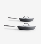 Two dark gray nonstick frying pans with glass lids and stainless steel handles