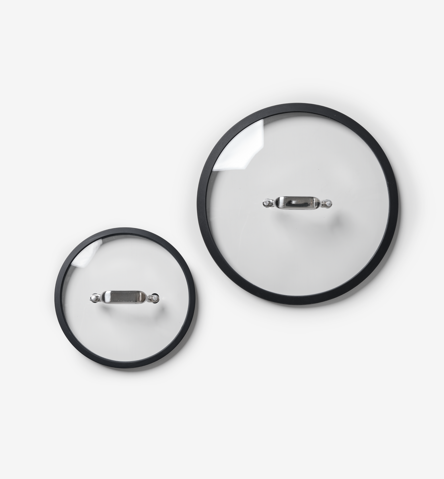 Two glass pot lids with black rim and stainless steel handle, small and large sizes