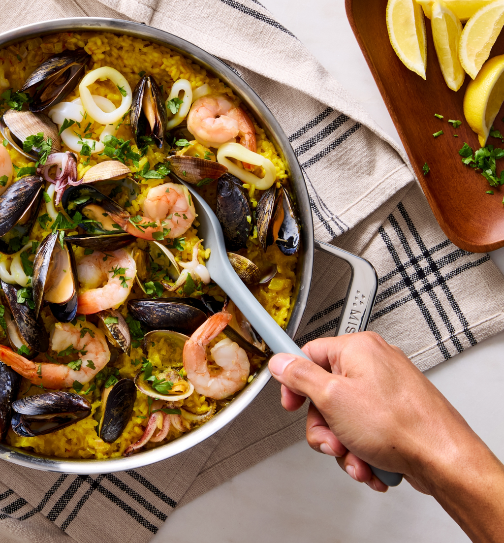 Seafood paella with mussels, shrimp, and squid in a stainless steel pan