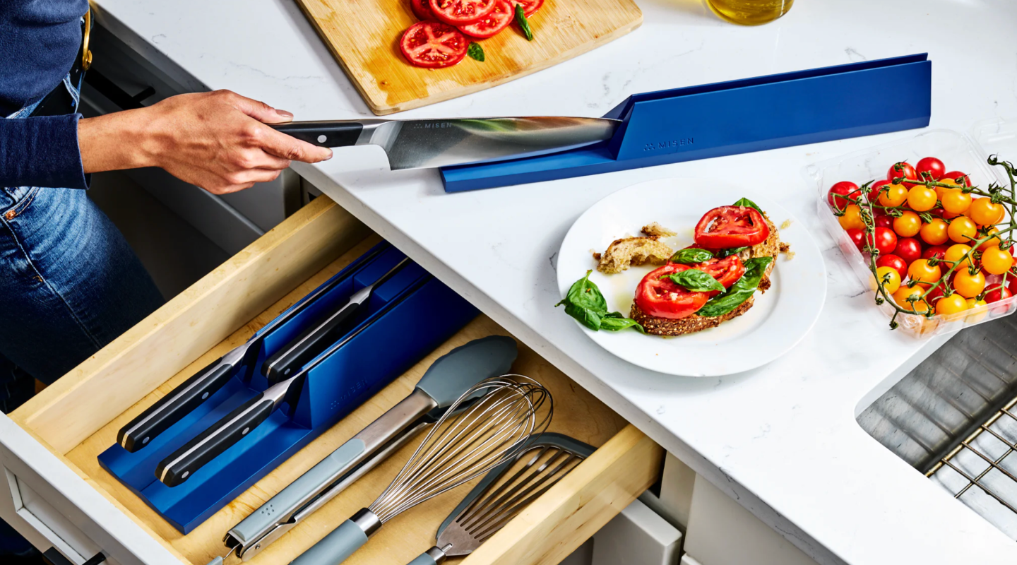 Misen knife being removed from blue drawer knife organizer in modern kitchen with tomato bruschetta