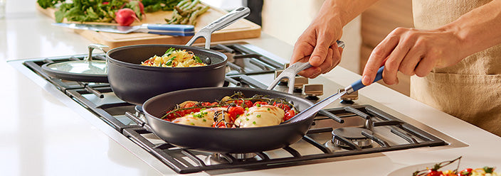 A hand uses a Misen Spatula to stir scrambled eggs in a Misen Nonstick Pan on a stovetop.