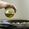 Pouring olive oil atop brussels sprouts in a Misen Stainless Steel Skillet