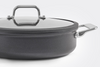 A zoomed in view of the Misen 3 QT Nonstick Sauté Pan’s side handle, with half of the pan and lid visible, on a white background.