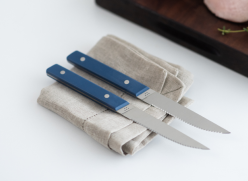 Two blue Misen steak knives atop a linen napkin