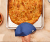 A bird’s eye view of a hand inside a Misen Pot Holder gripping a Misen Sheet Pan that contains a freshly-baked slab of focaccia bread.