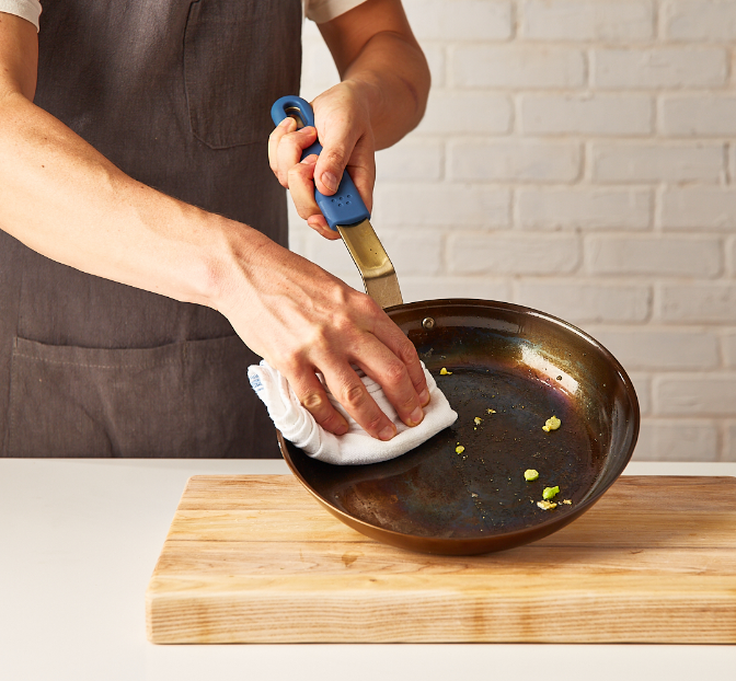 Wiping a Misen Pre-Seasoned Carbon Steel pan clean before hand washing.