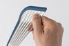 Close view of hand pinching the slotted metal surface of a Blue Misen Silicone Fish Spatula’s head.