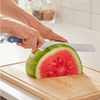 Using a blue Misen eight inch serrated knife to cut a watermelon