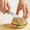 Using a blue, Misen, five inch, short serrated knife to cut a sesame seed bagel sandwich in half