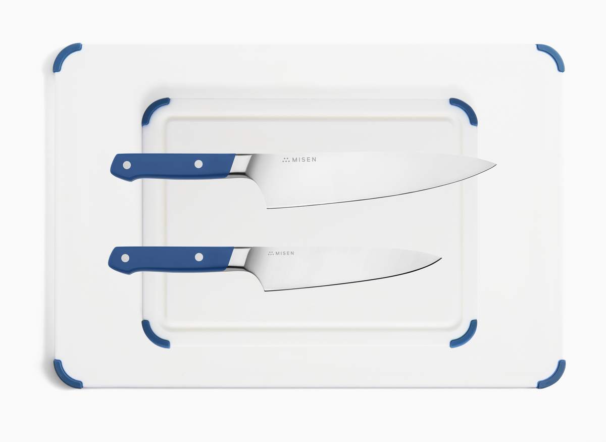 The Misen Knife Starter Kit contains a blue Chef Knife, a blue Utility Knife and a two piece Plastic Cutting Board Set