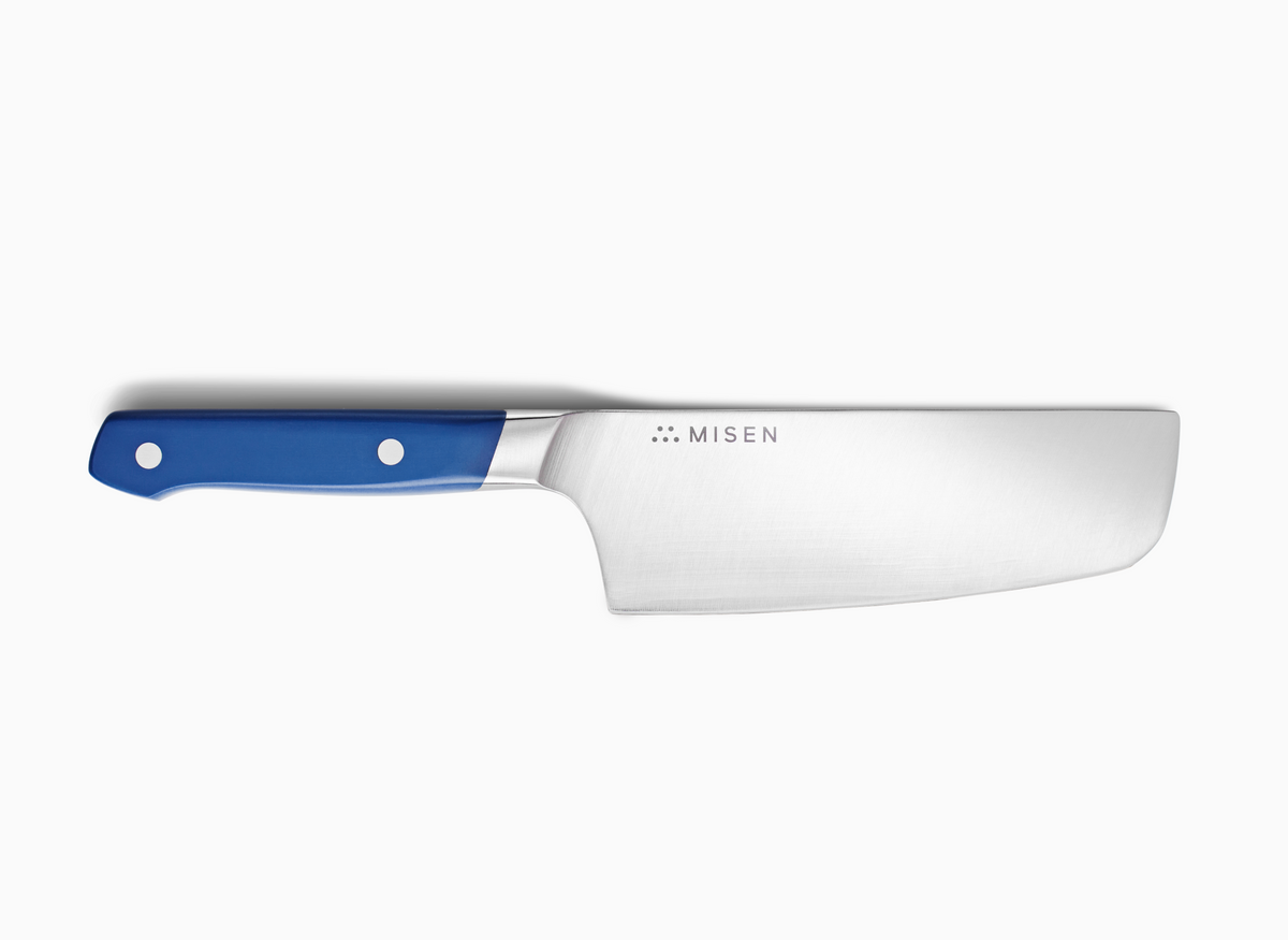The image depicts a Misen Nakiri knife with a blue handle on a white background. The word "MISEN" is visible on the knife's blade, near the handle.