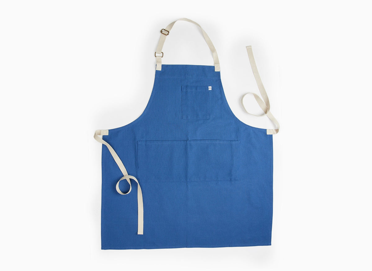 A blue Misen apron lies flat on a white background.