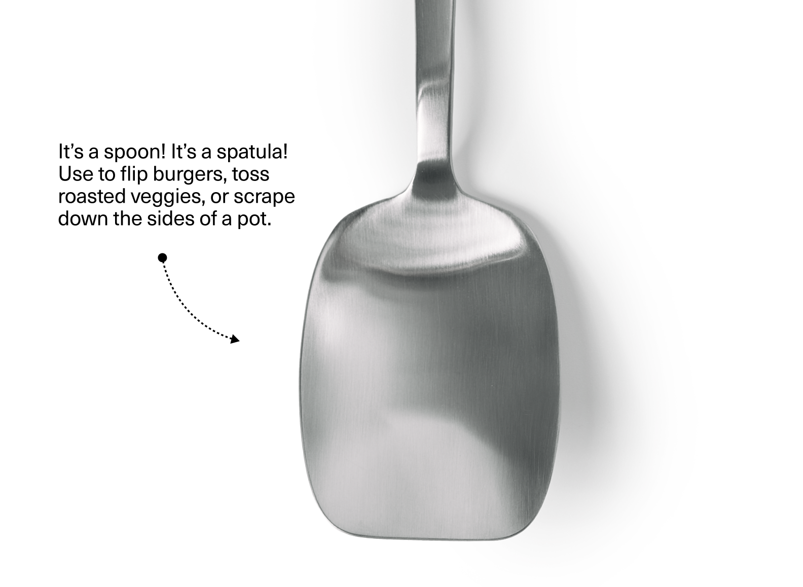 The image shows the wide, flat, and rectangular head of a stainless steel scraper-spoon, positioned vertically against a white background. The spoon head has gently curved edges and a matte or brushed finish. To the left of the spoon head, there is text that reads: "It's a spoon! It's a spatula! Use to flip burgers, toss roasted veggies, or scrape down the sides of a pot." Below the text, a dotted line with an arrow points towards the spoon head.