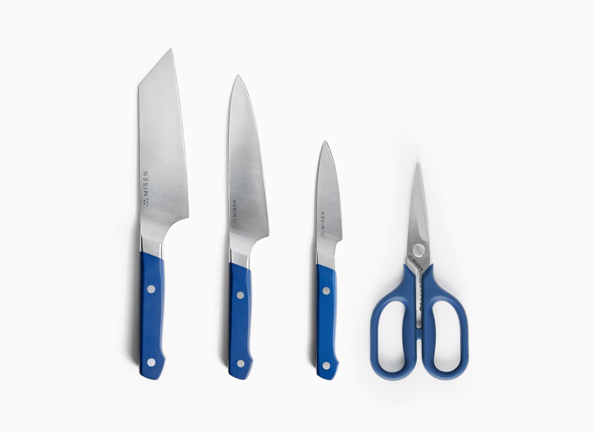 Four blue-handled Misen knives and kitchen shears are arranged in a row against a white background. From left to right, they are a 6 inch Bunka Knife, a 5.5 inch Utility Knife 2.0, a 3.5 inch Paring Knife 2.0, and a pair of small Kitchen Shears. The blades of the knives are all facing to the right, and the brand name "MISEN" is visible on the ACUTO440 steel knife blades and stainless steel shears.