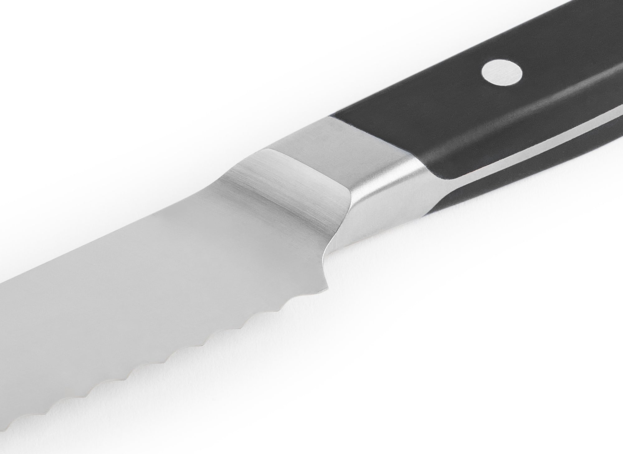 A close-up shot of the black Misen Short Serrated Knife on a white background, with a clear view of the blade serrations and sloped bolster.