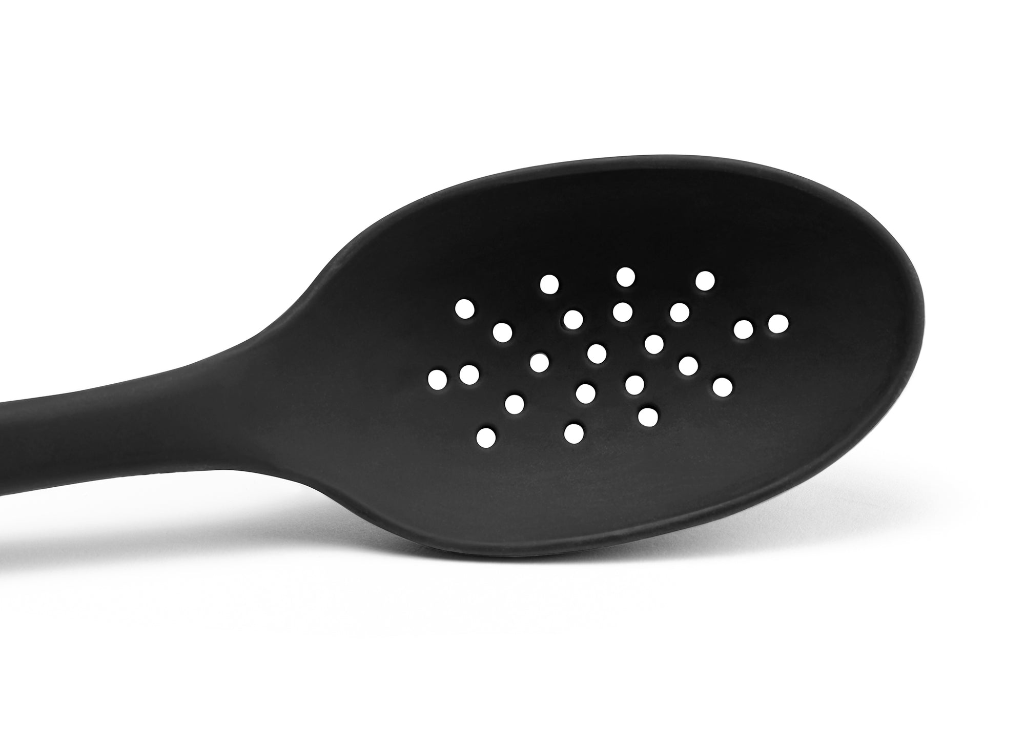 A close view from the front of a Black Misen Slotted Spoon’s head with drainage holes visible on a white background.