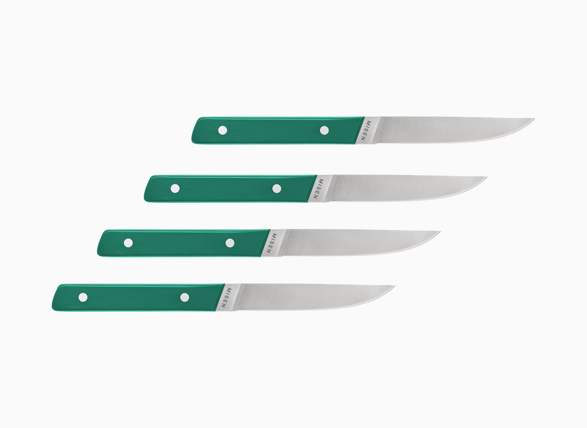 Set of four straight edge Misen ACUTO steak knives with green handles on a white background