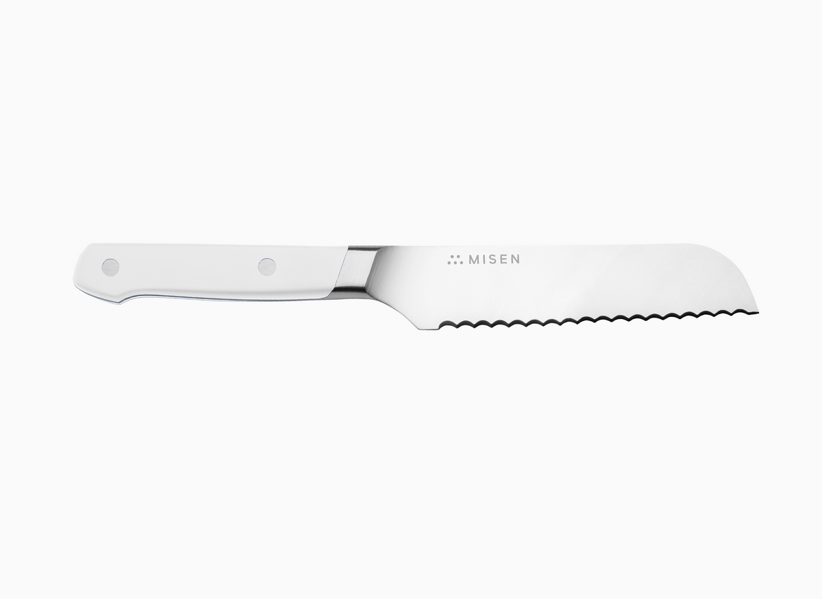A side view of a white Misen Short Serrated Knife on a white background.