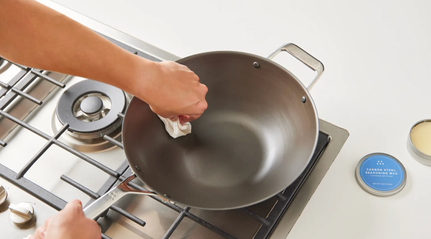 Seasoning a carbon steel wok with seasoning wax on a gas stovetop