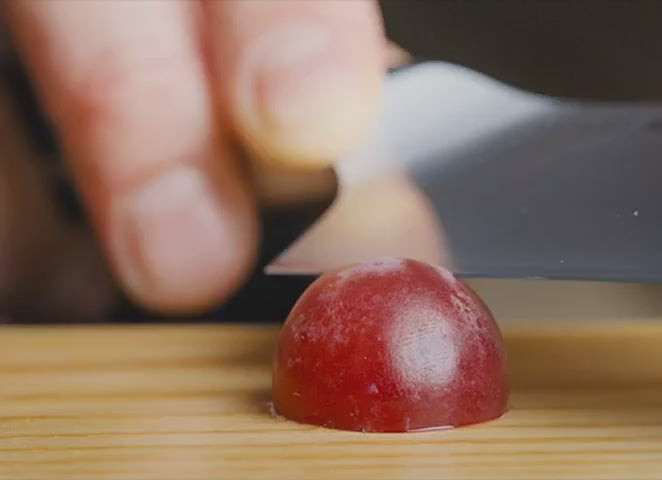 Demonstrating that a Misen Chef's Knife is sharp enough to cut a grape into paper thin slices.