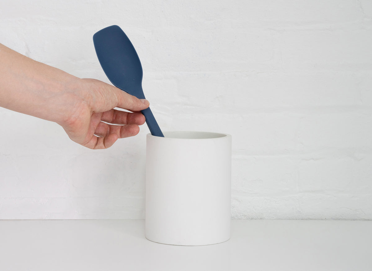 {{cream}} A hand grabbing a Blue Misen Spoontula from a White Misen Prep Tool Holder on a white countertop.