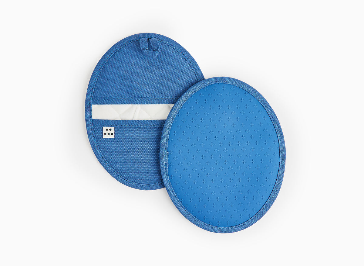 A front-facing view of two Misen Pot Holders in blue on a white background. One potholder shows the gripped side, the other shows the back opening and hanging loop.