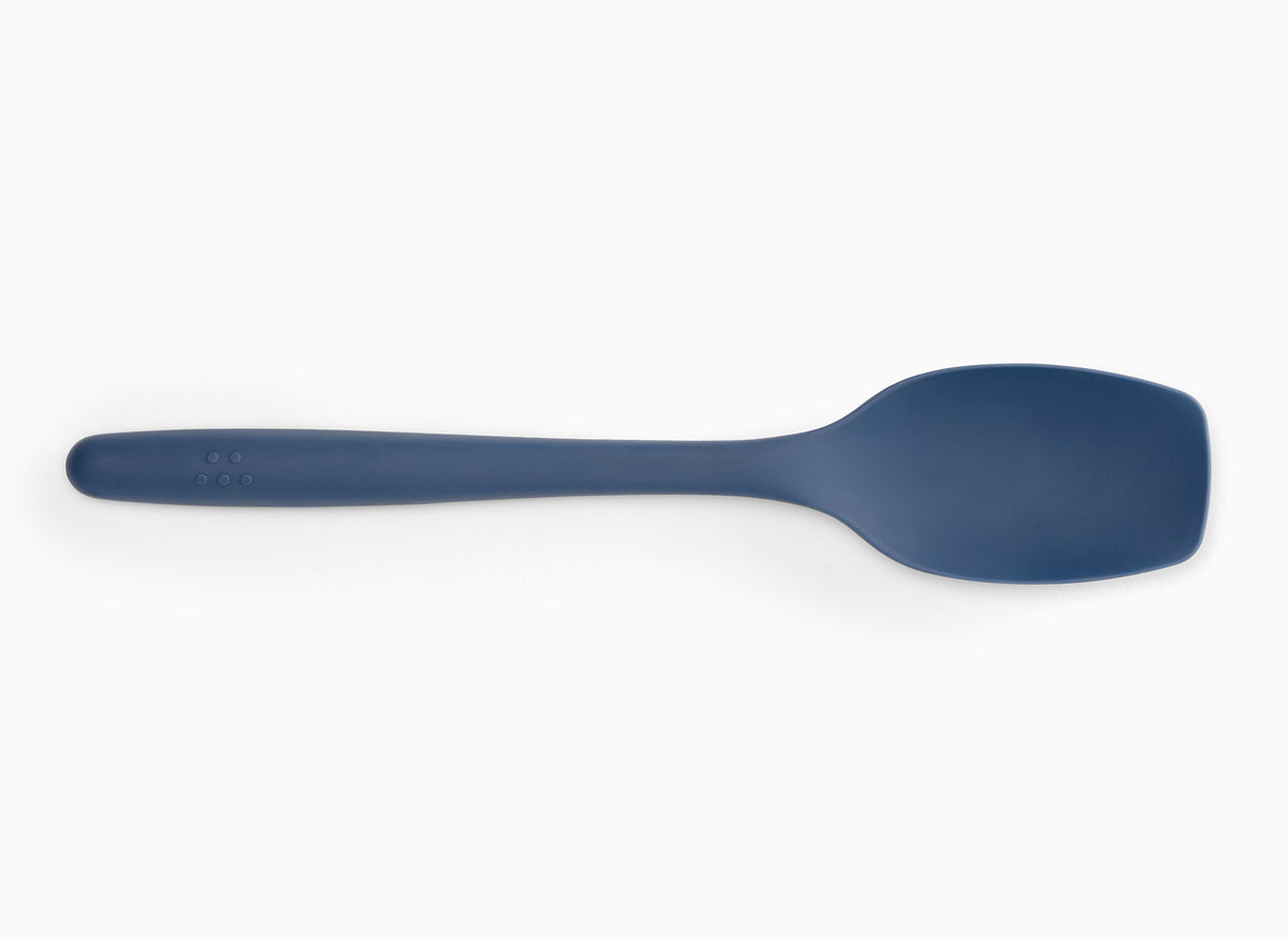 Blue Misen Spoontula seen from above on a white background. A curved spoon-like head with rounded corner edges and a long handle.